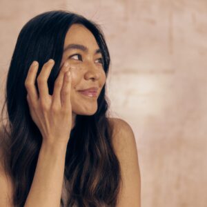 Frau trägt eine leichte Tagespflege auf als Symbol für minimalistische Hautpflege, Underconsumption Core und bewusste Skincare-Routinen.